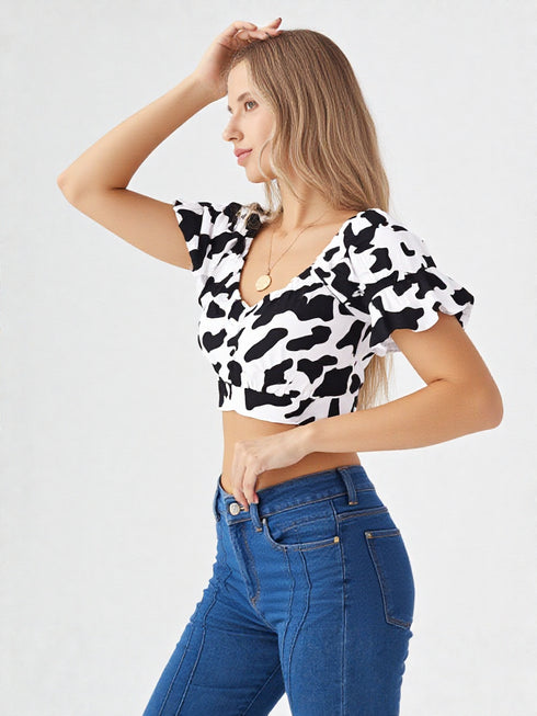 Woman wearing white cow print ruched puff sleeve crop top with puff sleeves and denim jeans