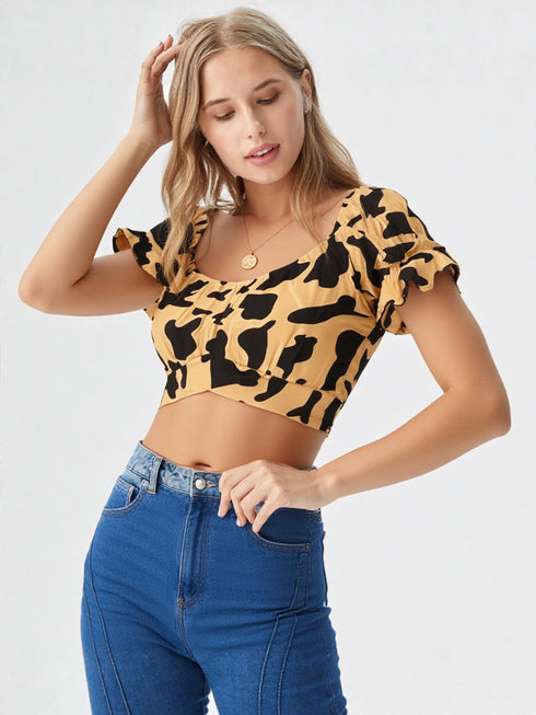Woman wearing yellow and black cow print puff sleeve ruched crop top