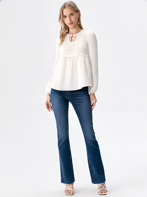 Close-up of woman wearing white ruffle detail tie neck blouse with long sleeves