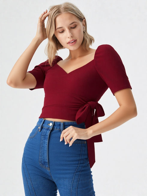 Woman wearing a wine red puff sleeve wrap top with tie waist