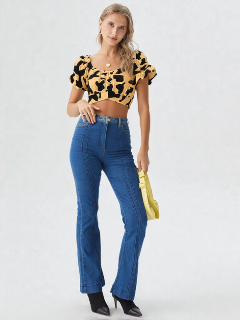 Woman wearing yellow and black cow print puff sleeve ruched crop top