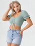Woman wearing mint green ruched drawstring puff sleeve crop top with denim shorts