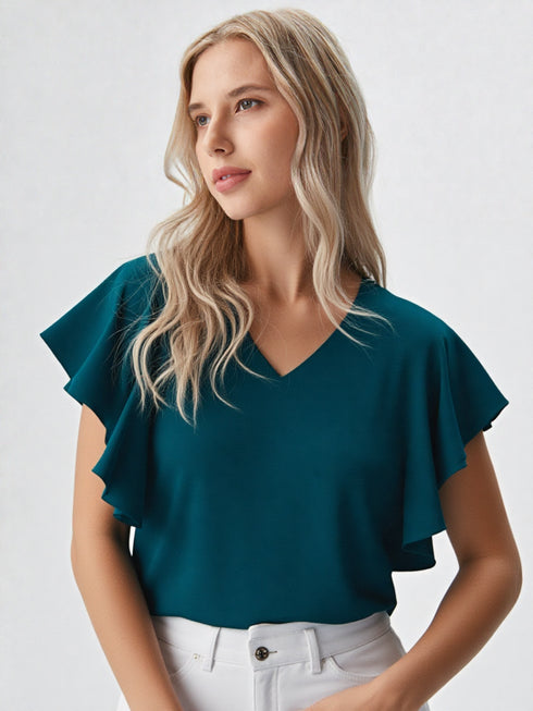 Woman wearing a green ruffle sleeve v-neck top paired with denim jeans
