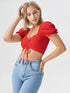Woman wearing a red puff sleeve ruched crop top paired with light blue denim jeans