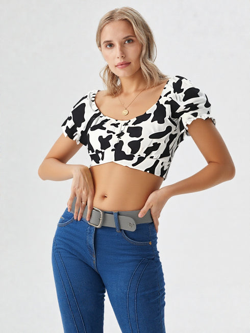 Woman wearing white cow print ruched puff sleeve crop top with puff sleeves and denim jeans