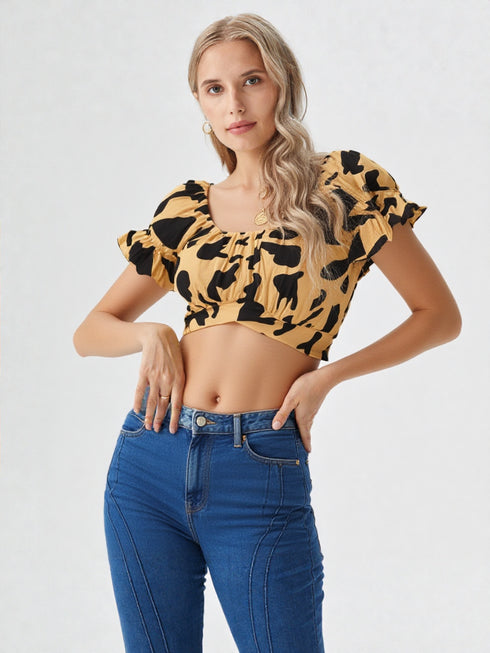 Woman wearing yellow and black cow print puff sleeve ruched crop top