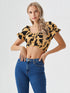 Woman wearing yellow and black cow print puff sleeve ruched crop top