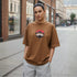 Model wearing brown oversized cotton t-shirt with anime-inspired front graphic print
