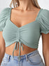 Woman wearing mint green ruched drawstring puff sleeve crop top with denim shorts