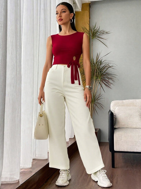 Woman wearing wine red side tie sleeveless crop top with white high-waisted trousers