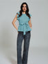Woman wearing sea green ruffle sleeve belted peplum top with black trousers