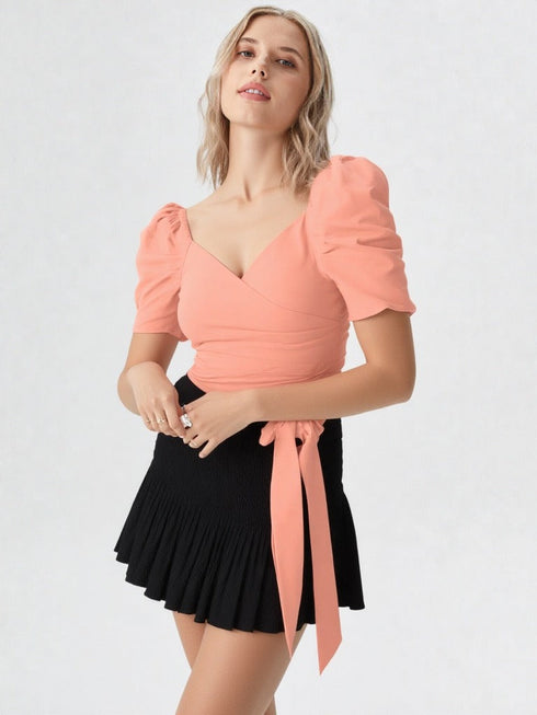 Woman wearing a peach puff sleeve wrap top with tie waist