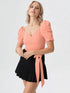 Woman wearing a peach puff sleeve wrap top with tie waist