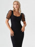 Woman wearing a black puff sleeve mesh midi dress with polka-dot sheer sleeves