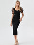 Woman wearing a black puff sleeve mesh midi dress with polka-dot sheer sleeves