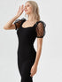 Woman wearing a black puff sleeve mesh midi dress with polka-dot sheer sleeves