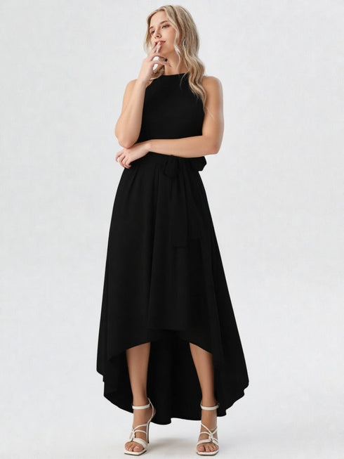 Woman wearing black halter neck asymmetrical maxi dress with tie waist belt and white heels