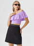 Woman wearing lavender one shoulder ruffle crop top with black skirt
