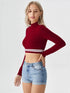 Woman wearing wine red mock neck long sleeve crop top with striped hem paired with denim shorts