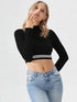 Woman wearing black mock neck long sleeve crop top with striped hem paired with blue jeans