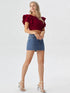 Woman wearing wine red ruffle sleeve crop top with light denim shorts