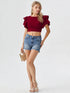 Woman wearing wine red ruffle sleeve crop top with light denim shorts