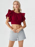 Woman wearing wine red ruffle sleeve crop top with light denim shorts