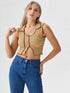 Woman wearing camel contrast stitch sleeveless crop top with wavy hem and blue jeans