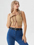 Woman wearing camel contrast stitch sleeveless crop top with wavy hem and blue jeans