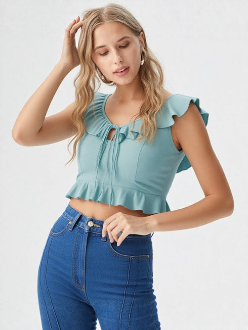 Woman wearing sea green ruffle trim tie front crop top with high-waisted jeans