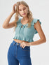 Woman wearing sea green ruffle trim tie front crop top with high-waisted jeans