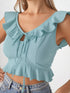 Woman wearing sea green ruffle trim tie front crop top with high-waisted jeans