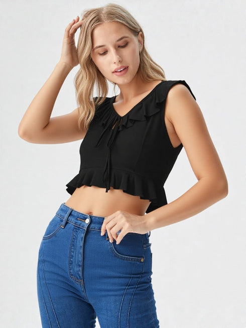 Woman wearing a black ruffle tie-front crop top with peplum hem and blue jeans