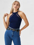 Close-up of woman wearing navy blue halter neck cutout top with black belt and denim jeans