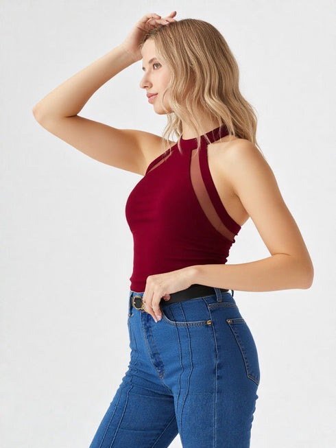 Woman wearing wine red halter neck cutout top with black belt and blue jeans