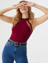 Woman wearing wine red halter neck cutout top with black belt and blue jeans