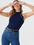 Close-up of woman wearing navy blue halter neck cutout top with black belt and denim jeans
