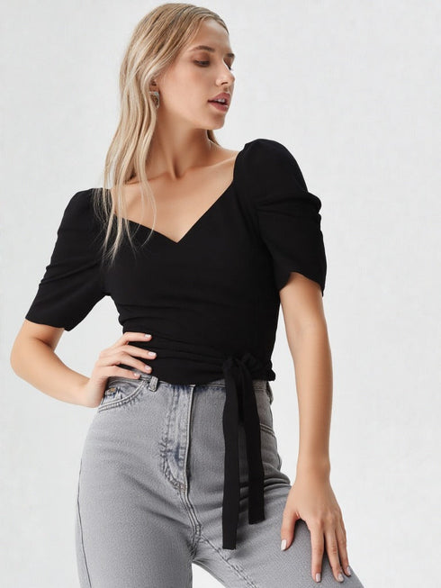 Woman wearing a black puff sleeve wrap top with tie waist