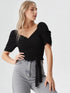 Woman wearing a black puff sleeve wrap top with tie waist