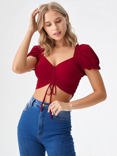 Woman wearing a wine red ruched puff sleeve crop top with tie front