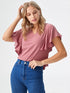 Woman wearing rose pink flutter sleeve V-neck polyester top styled with blue jeans