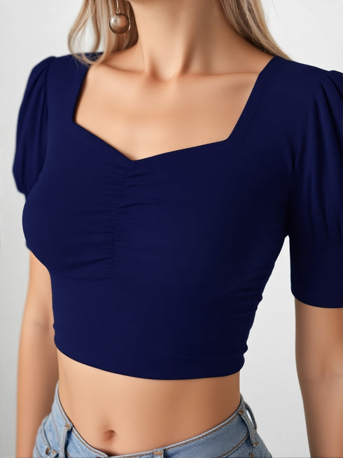 Woman wearing navy blue square neck ruched puff sleeve crop top with blue jeans