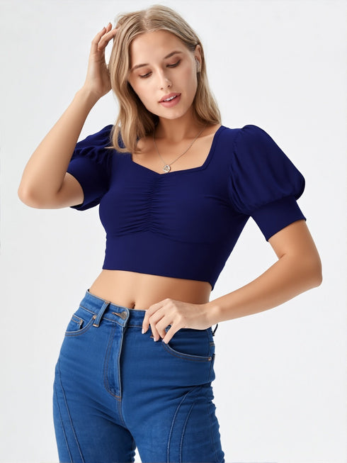 Woman wearing navy blue square neck ruched puff sleeve crop top with blue jeans