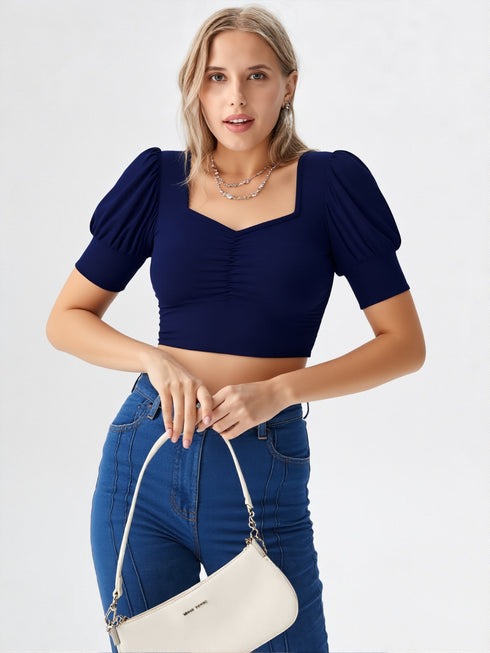 Woman wearing navy blue square neck ruched puff sleeve crop top with blue jeans