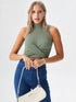 Woman wearing green sleeveless ribbed wrap crop top with high-waisted jeans