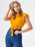 Woman wearing mustard yellow ruffle sleeve belted top with blue jeans