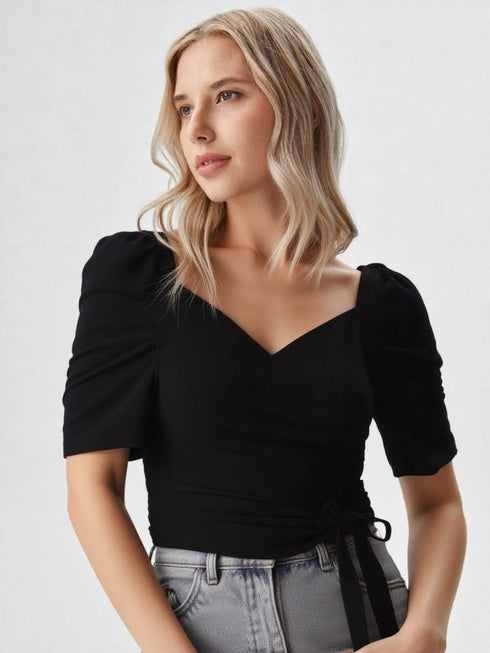Woman wearing a black puff sleeve wrap top with tie waist