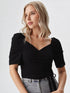 Woman wearing a black puff sleeve wrap top with tie waist