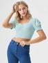 Woman wearing a sky blue ruched square neck puff sleeve crop top