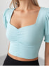 Woman wearing a sky blue ruched square neck puff sleeve crop top